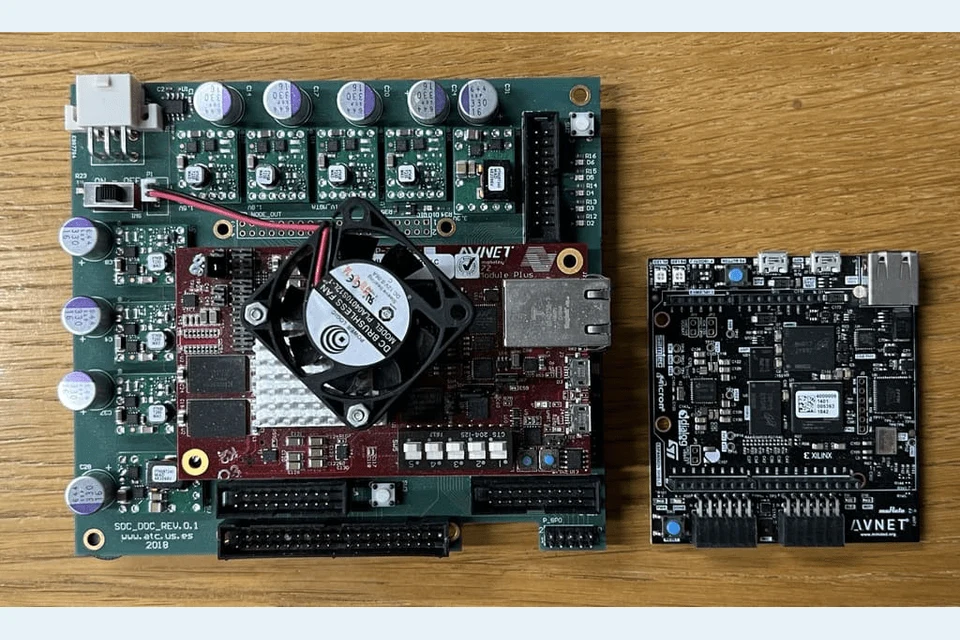 The physical FPGA boards used for Spartus and Edge-Spartus on a wooden tabletop.